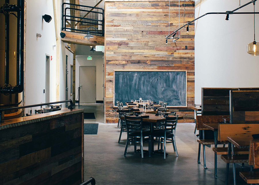 A cedar plank wall featuring a huge chalkboard sits behind a private seating area